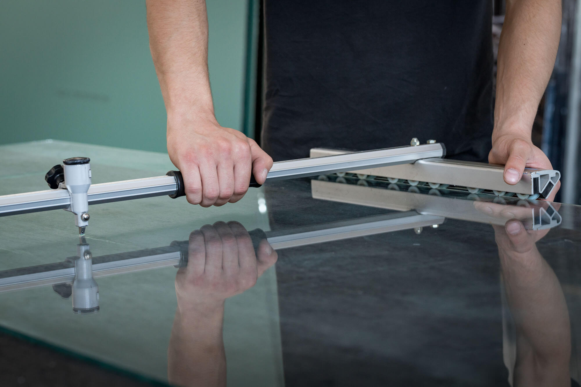 Technician carefully cutting a large pane of glass.