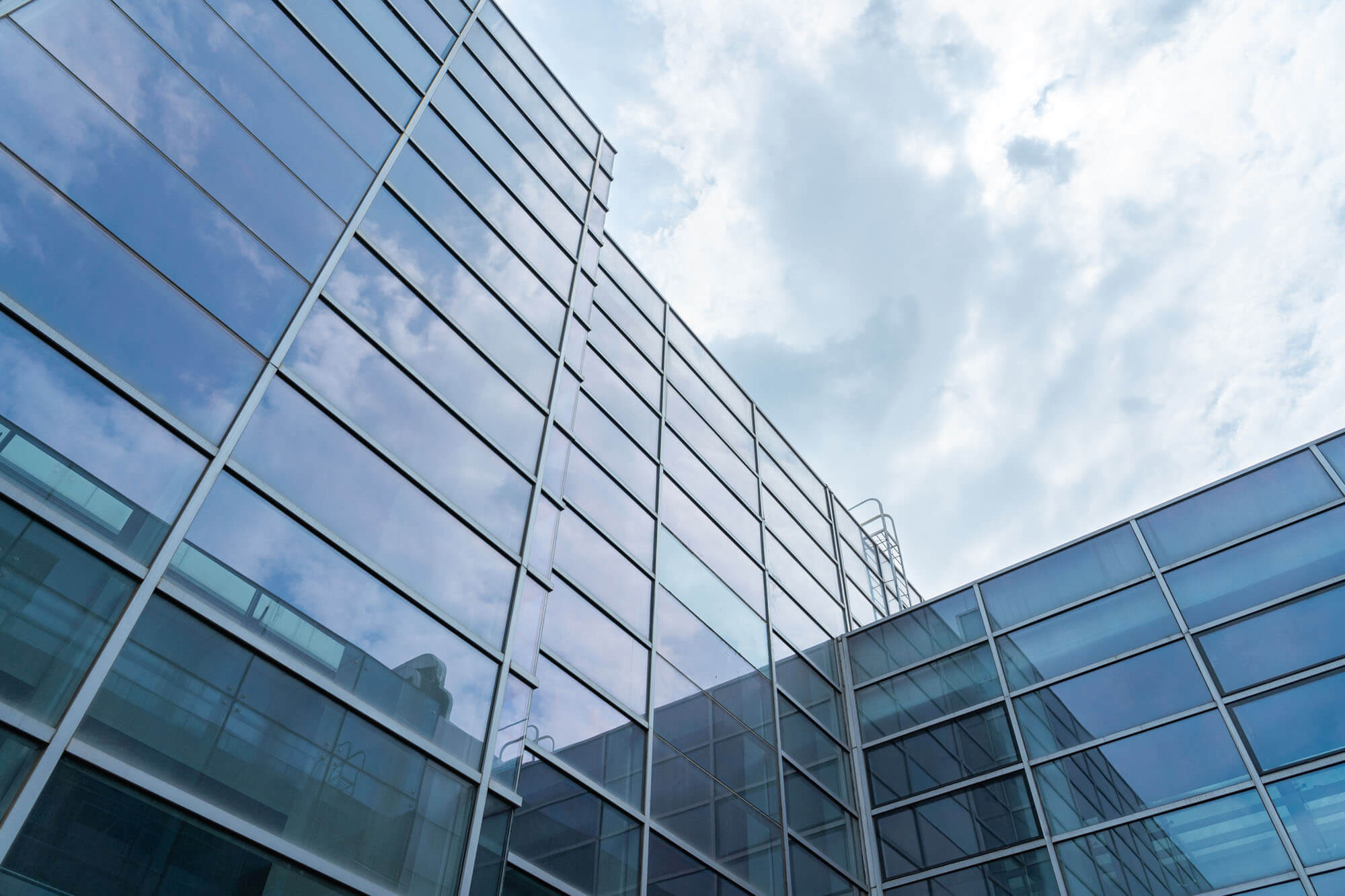 Looking up at a tall building with a glass curtain wall.